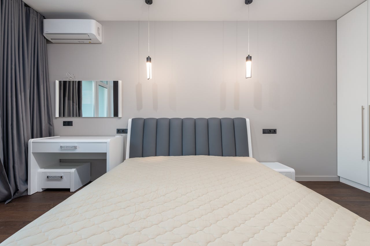 Sleek minimalist bedroom design featuring a plush bed, pendant lighting, and modern furnishings.